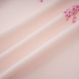 A pink midi dress with a floral print pattern worn by a model standing against a plain background
