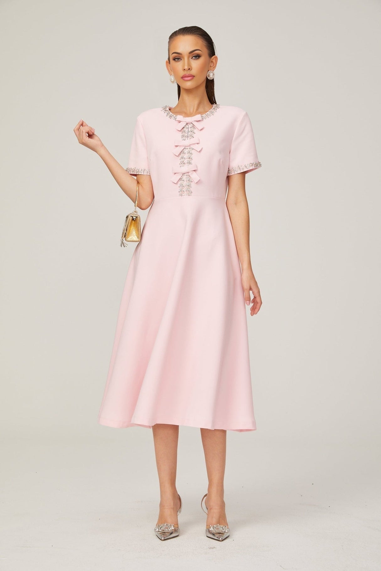 A pink midi dress with a large bow detail and crystal accents inspired by the Cassiopeia constellation