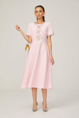 A pink midi dress with a large bow detail and crystal accents inspired by the Cassiopeia constellation