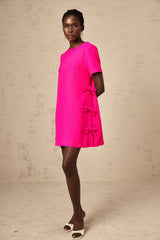 A pink mini dress with a bow detail featuring a feminine and playful design