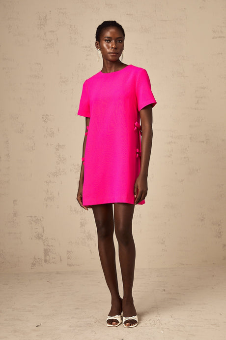 A pink mini dress with a bow detail featuring a feminine and playful design
