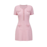 A pink mini dress with a knit fabric adorned with beaded embellishments featuring a feminine and elegant design