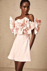 A pink mini dress with an offshoulder design featuring three dimensional floral petal details named Juliette