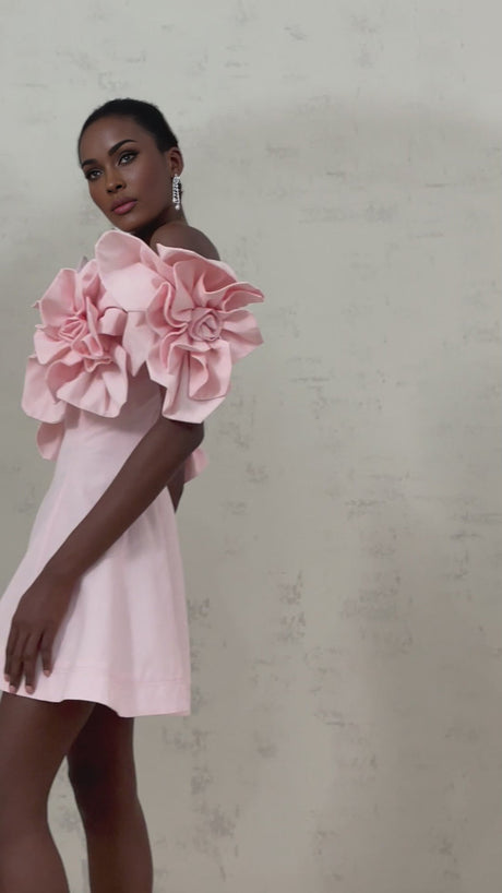 A pink mini dress with an offshoulder neckline adorned with threedimensional floral petals named Juliette