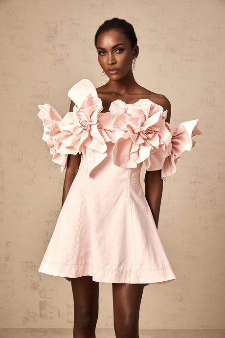 A pink mini dress with an offshoulder neckline featuring three dimensional petal embellishments and a short hemline