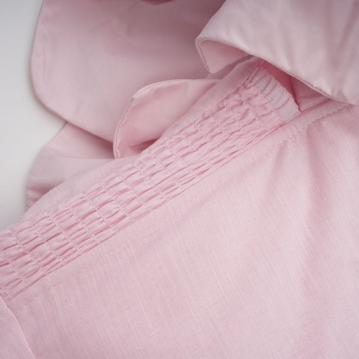 A pink mini dress with an offshoulder neckline featuring threedimensional petal details on the bodice