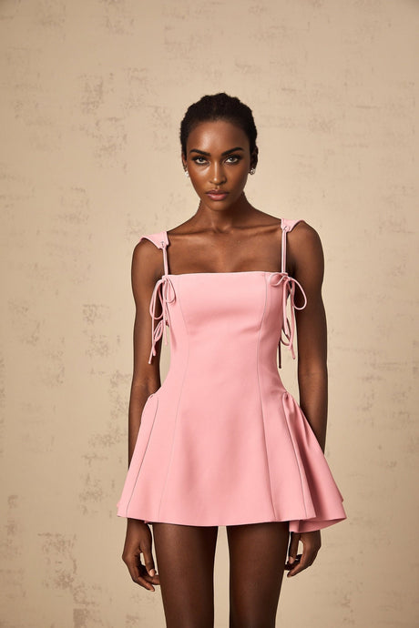 A pink mini dress with puff sleeves and a detachable strap featuring a fitted bodice and short skirt in a feminine Donatienne style