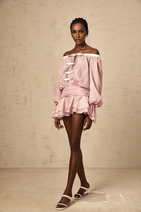A pink offshoulder mini dress with a bow detail and flounced design worn by a model