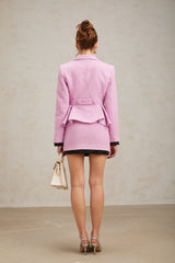 A pink tweed matching set featuring a top and skirt in a coordinated style with a feminine and sophisticated appearance