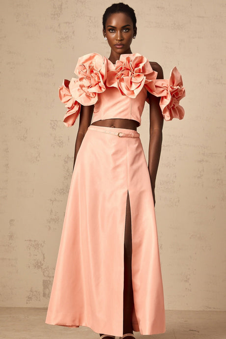 A pink twopiece outfit consisting of a top and skirt with floral applique details matching set by Yvette
