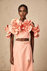 A pink twopiece outfit featuring a top and skirt with floral applique details matching set by Yvette