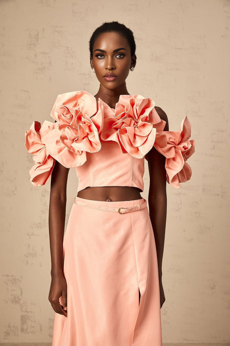 A pink twopiece outfit featuring a top and skirt with floral applique details matching set by Yvette