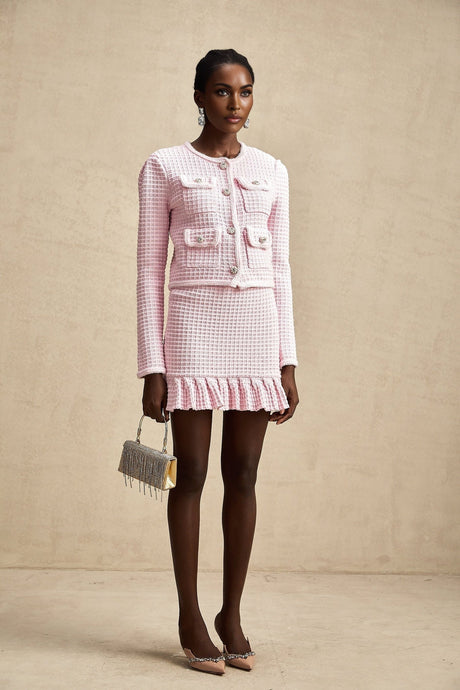 A pink waffle knit matching set consisting of a jacket and skirt called Fabienne The outfit has a textured pattern and is designed to be worn together as a coordinated ensemble
