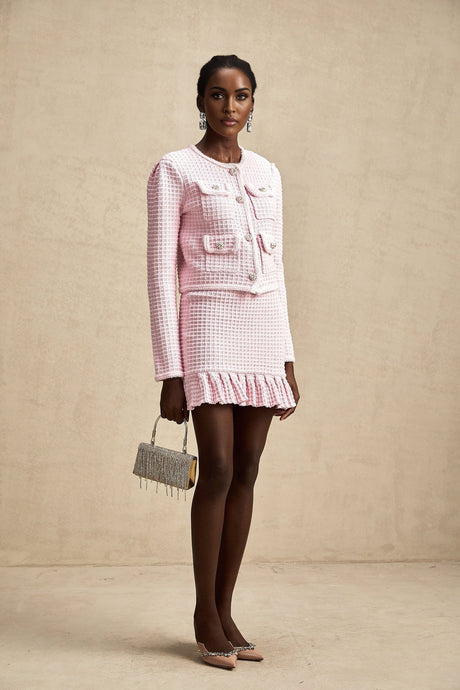 A pink waffle knit matching set consisting of a jacket and skirt named Fabienne The outfit is styled as a coordinated ensemble with a textured waffle pattern