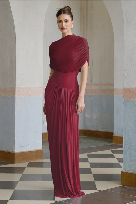 A red asymmetric maxi dress with pleated details and a long flowing skirt worn by a model
