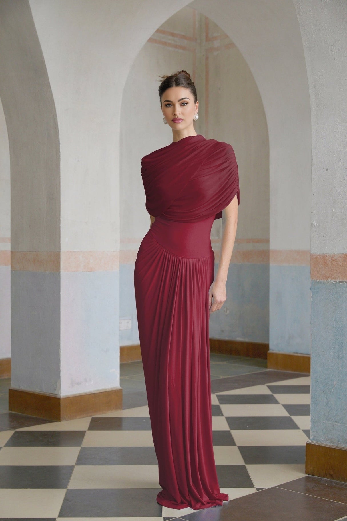 A red asymmetric maxi dress with pleated details and a long flowing skirt