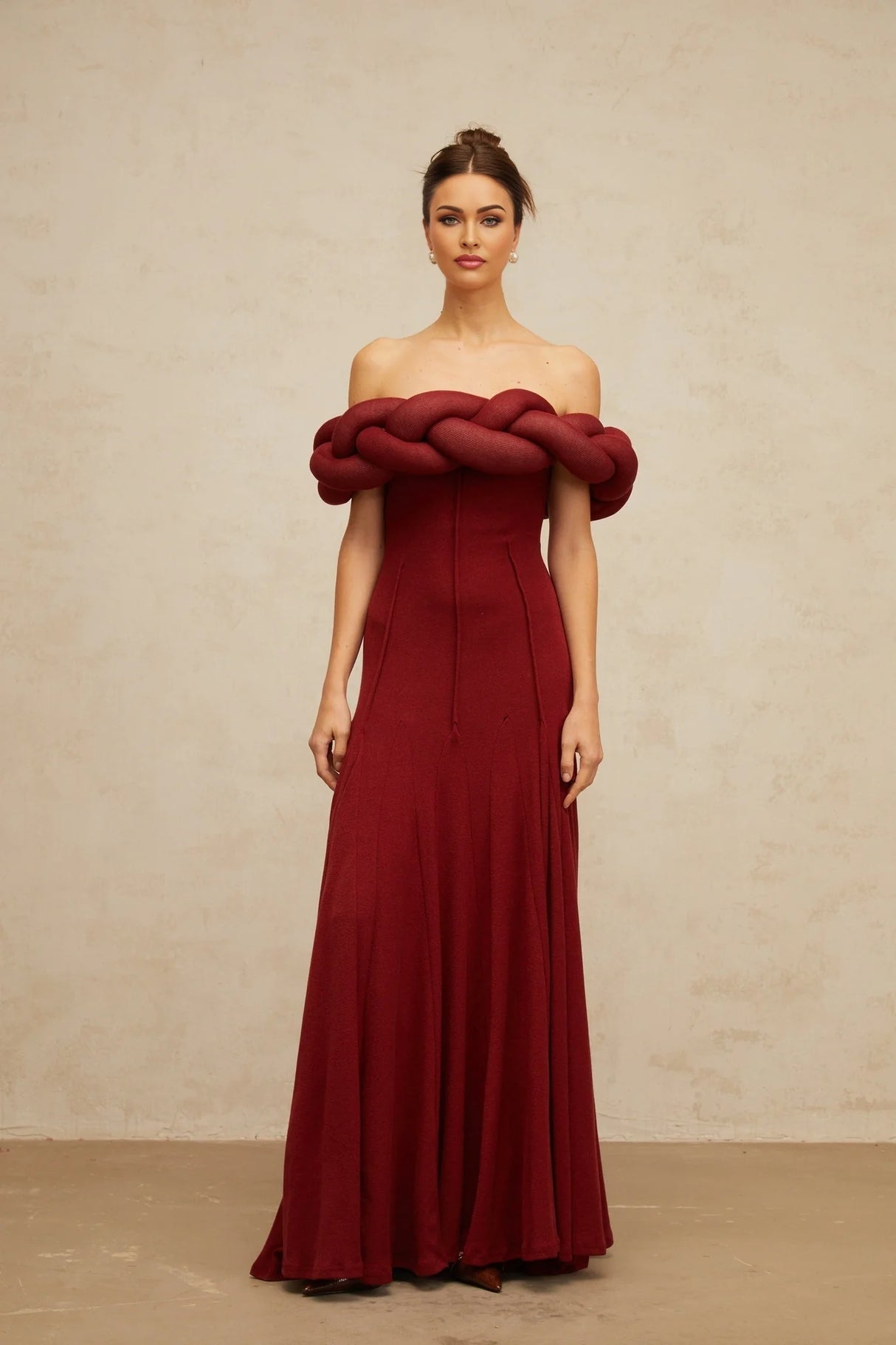 A red knitted maxi dress with braided design details featuring long sleeves and a floor length skirt