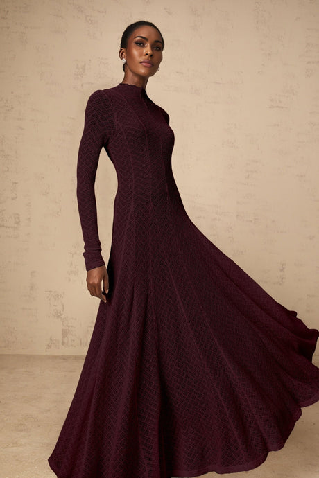 A red maxi dress with a wavy lace pattern covering the entire garment featuring a long flowing skirt and feminine silhouette