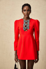 A red mini dress with a split skirt featuring a studded bow accent and a short hemline