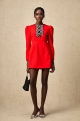 A red mini dress with a split skirt featuring a studded bow detail and a fitted silhouette