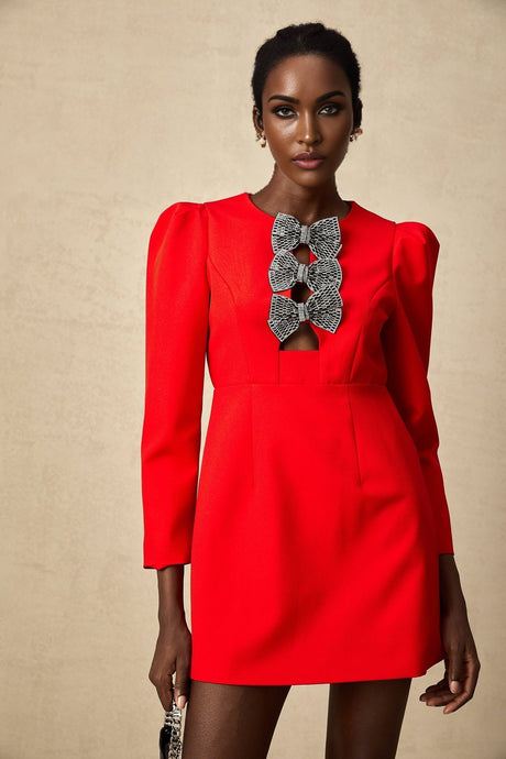 A red mini dress with a split skirt featuring a studded bow detail and a fitted silhouette