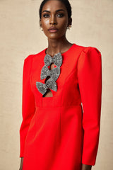 A red mini dress with a split skirt featuring a studded bow detail and a fitted silhouette