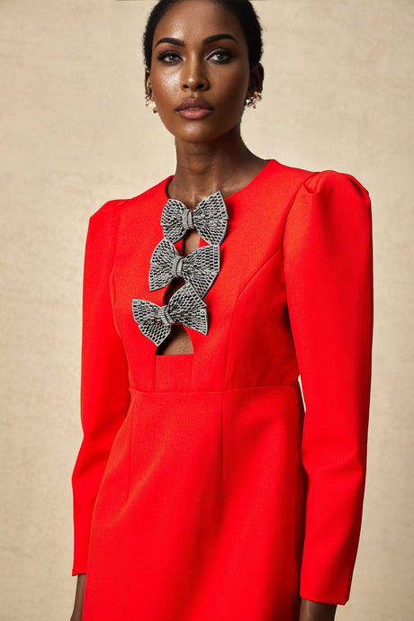 A red mini dress with a split skirt featuring a studded bow detail and a fitted silhouette