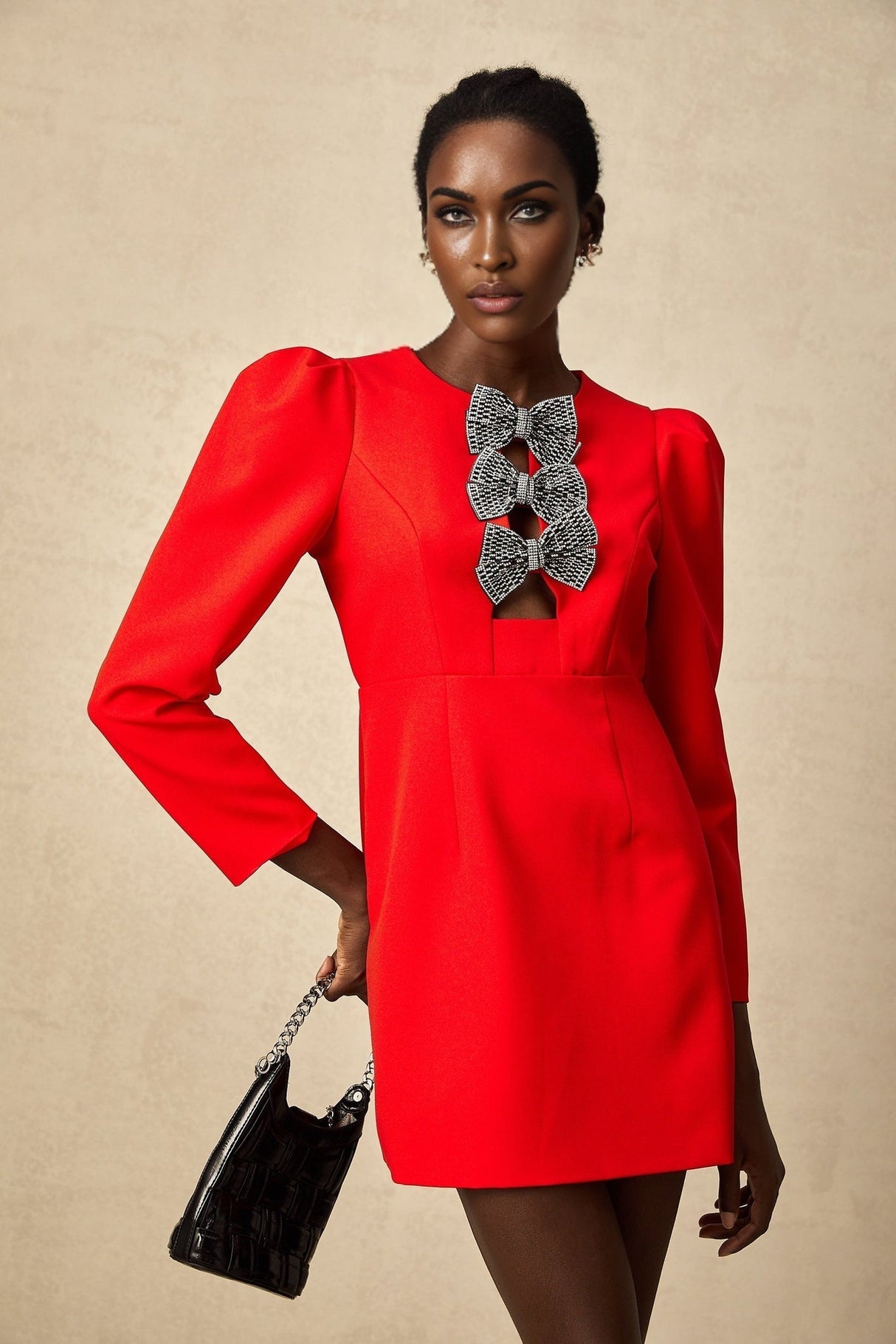 A red mini dress with a split skirt featuring a studded bow detail on the front