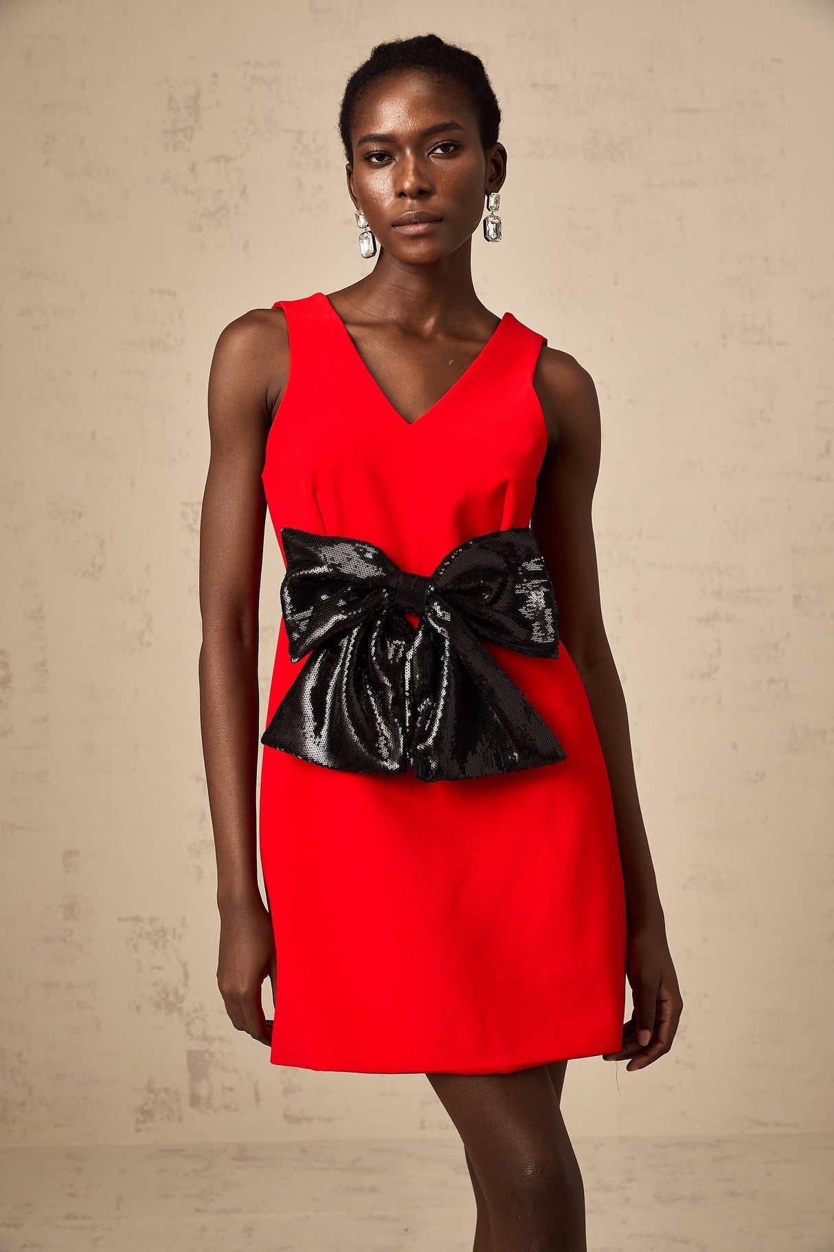 A red mini dress with a Vneckline featuring a sequin bow detail on the front