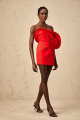 A red mini dress with an offshoulder neckline featuring a large sculptural rose detail on the bodice