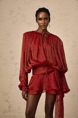 A red mini dress with full pleating and ruffled details named Eugenie