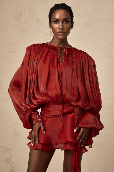 A red mini dress with full pleats and ruffles featuring a short hemline and feminine Eugenie style design
