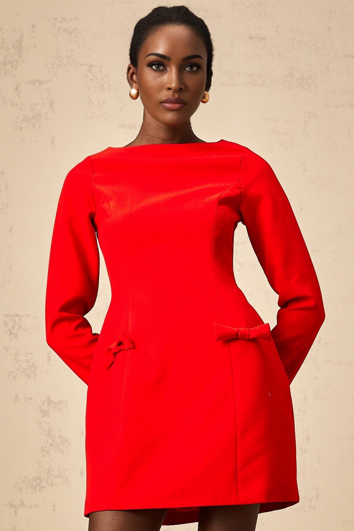 A red mini dress with long sleeves and a decorative bow detail at the neckline named Magali