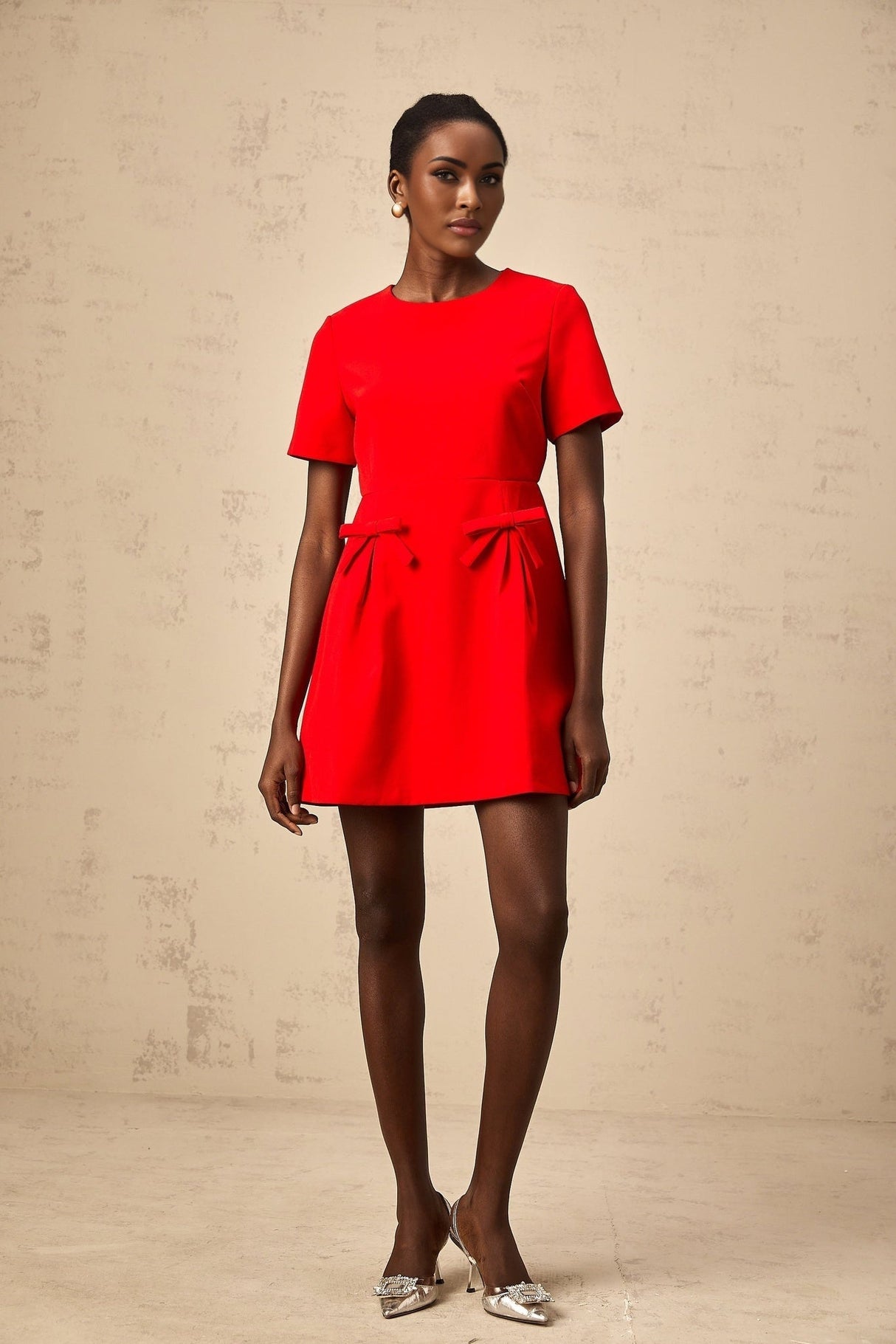 A red mini dress with short sleeves and a bow detail worn by a model