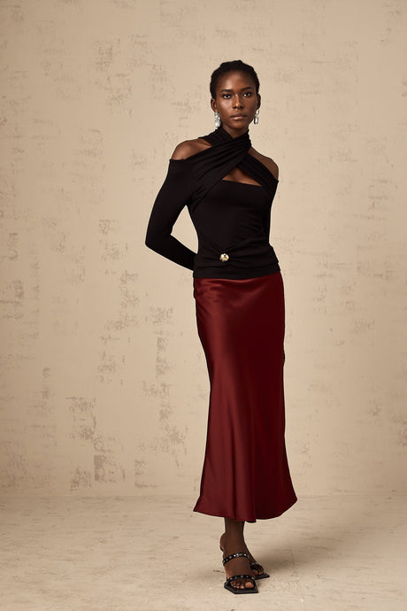 A red satin skirt with a flared silhouette hanging on a plain background
