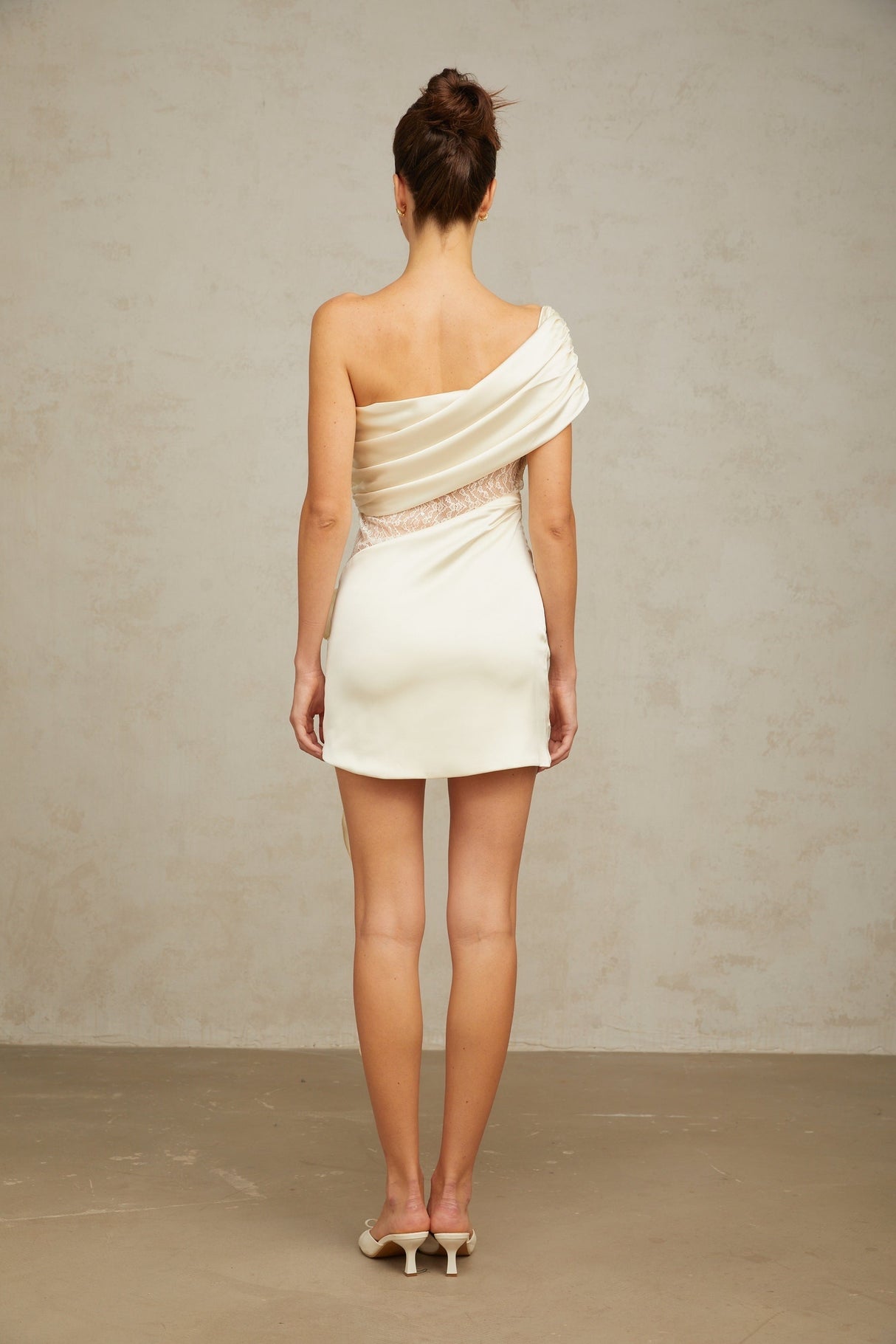 A short asymmetric dress in neutral tones featuring lace panels and a mini length