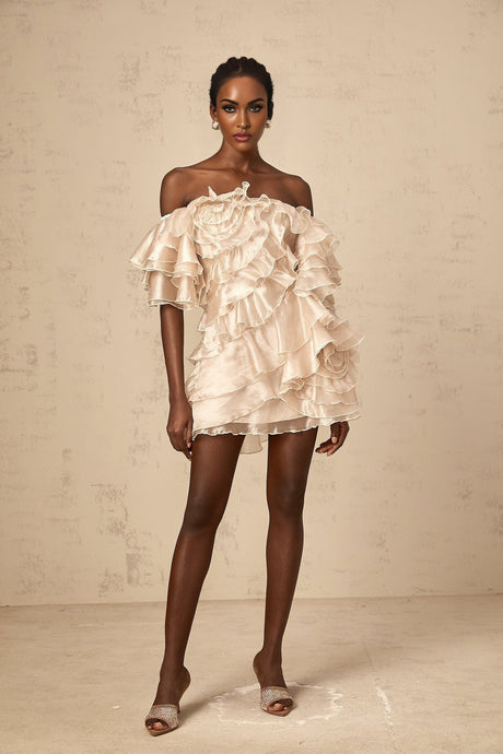 A short asymmetric mini dress in neutral tones featuring a cerise pink flounce detail and one shoulder design