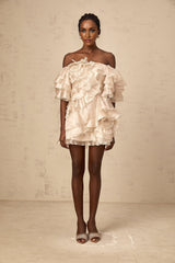 A short beige asymmetric dress with a ruffled flounce detail and one shoulder strap