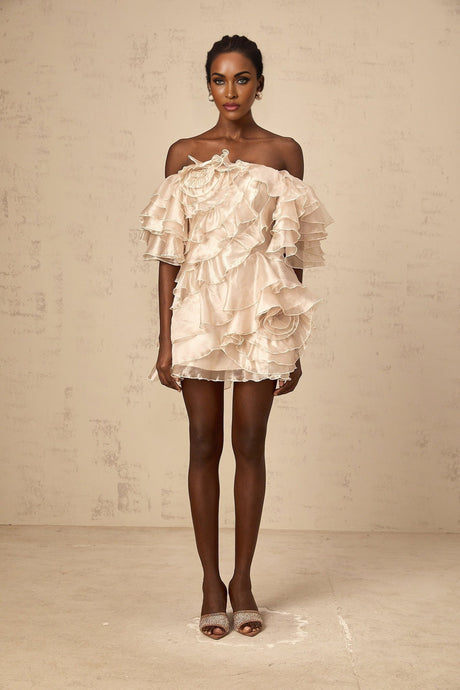 A short beige asymmetric dress with a ruffled flounce detail and one shoulder strap