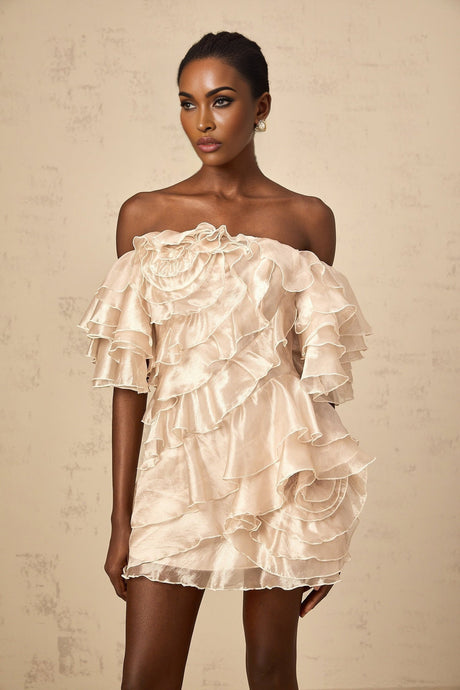 A short beige dress with an asymmetric design featuring a ruffled flounce detail and a mini length skirt