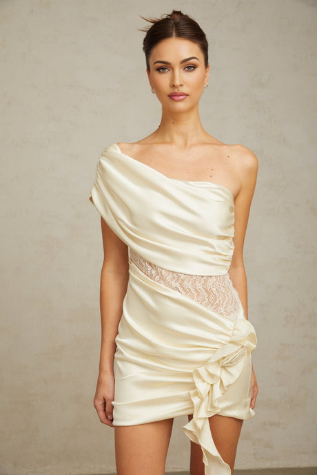 A short beige dress with asymmetric hem and lace panel details featuring thin straps and a fitted silhouette
