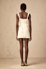 A short beige mini dress with butterfly prints and draped fabric details featuring a sleeveless design and a flowing silhouette