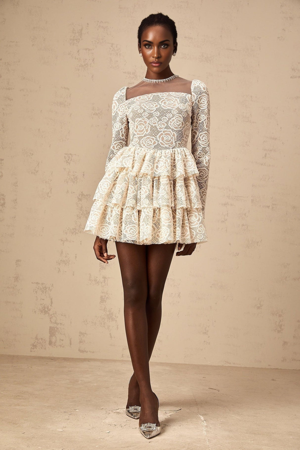A short beige mini dress with delicate floral embroidery featuring a fitted waist and short sleeves