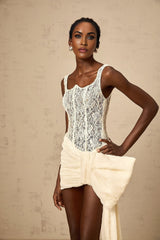 A short beige mini dress with floral lace details and a bow accent featuring a pencil skirt silhouette and neutral tones