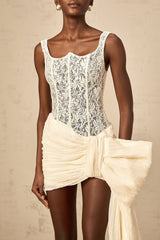 A short beige mini dress with floral lace details and a decorative bow accent