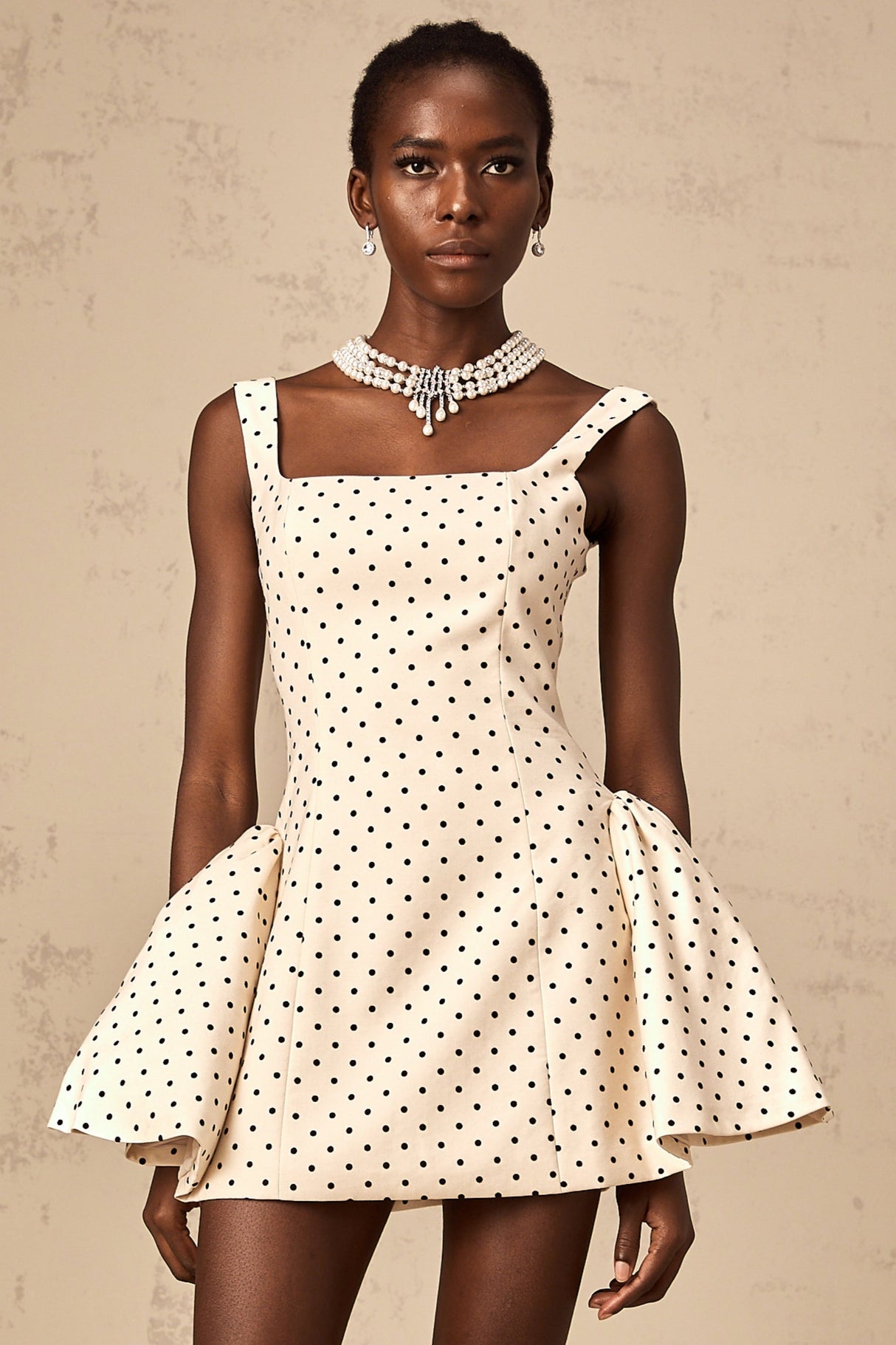 A short beige mini dress with polka dots and puff sleeves in a neutral color palette