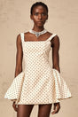 A short beige mini dress with polka dots and puff sleeves in a neutral color palette