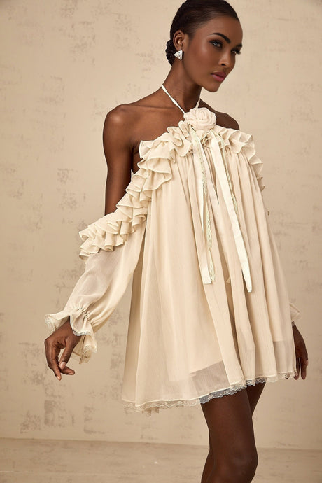 A short beige mini dress with ruffled layers and delicate floral applique details in neutral tones