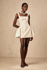 A short beige mini dress with small polka dots featuring puffed sleeves and a fitted waist