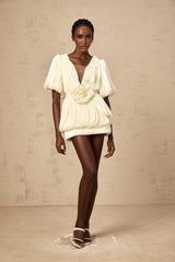 A short beige pleated dress with floral appliques and a mini length